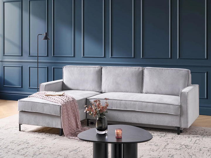 Gray sectional sofa in a living room with a dark blue paneled wall.