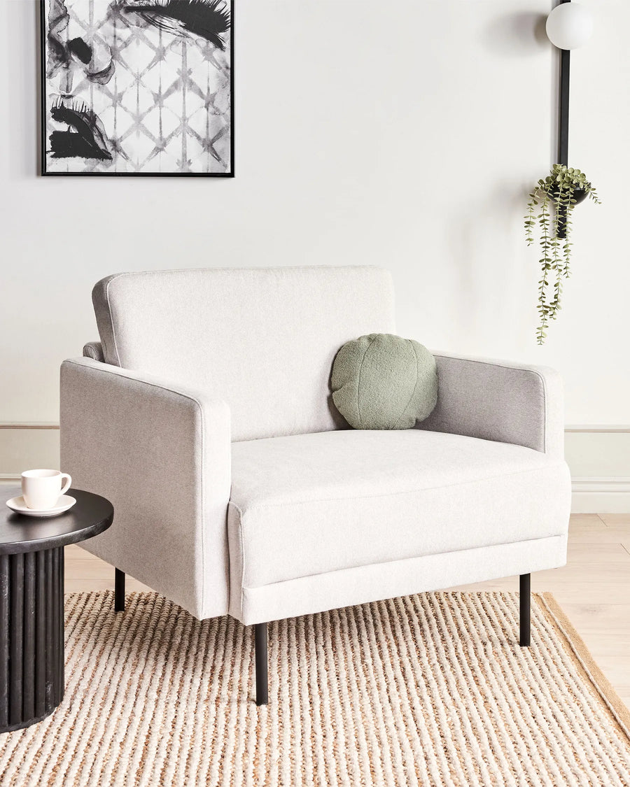 Gray armchair with a green cushion in a modern living room setting.