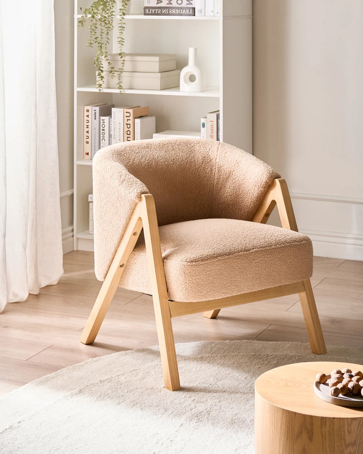 Beige armchair in a room with a bookshelf and small table.