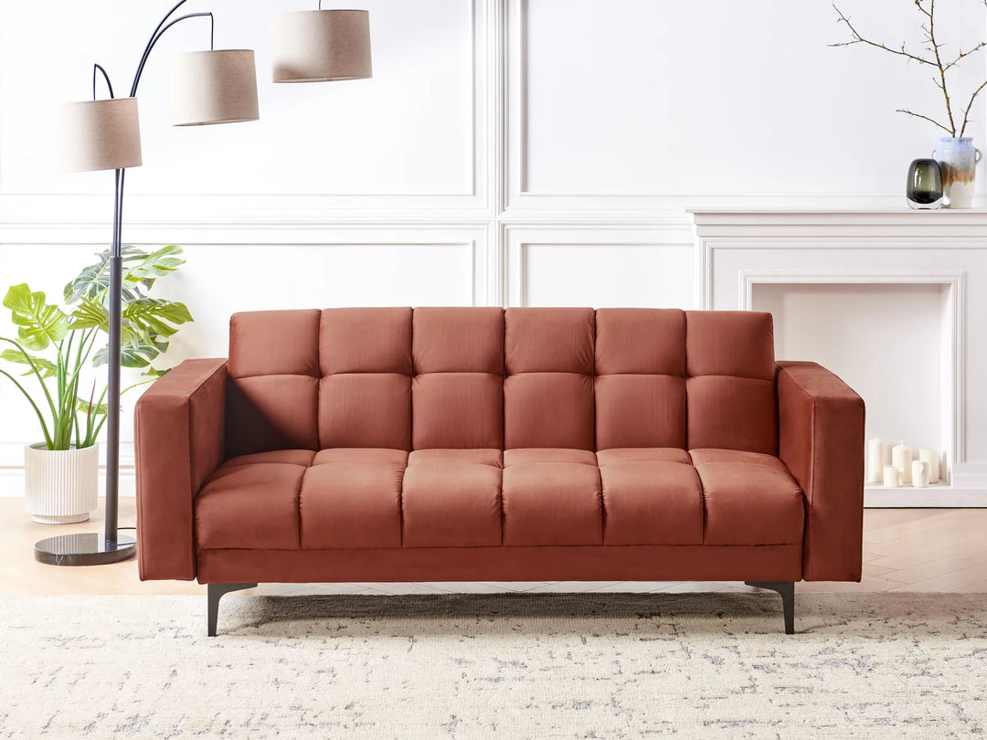 Brown sofa in a living room setting with a lamp and plants.