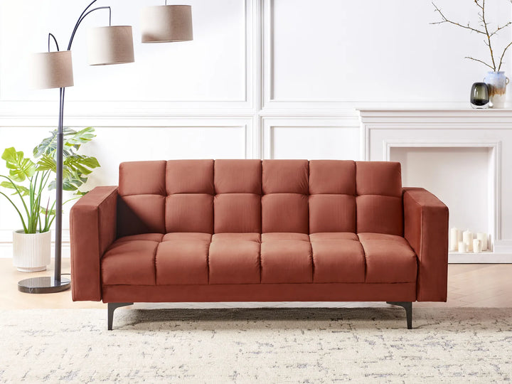 Brown sofa in a living room setting with a lamp and plants.