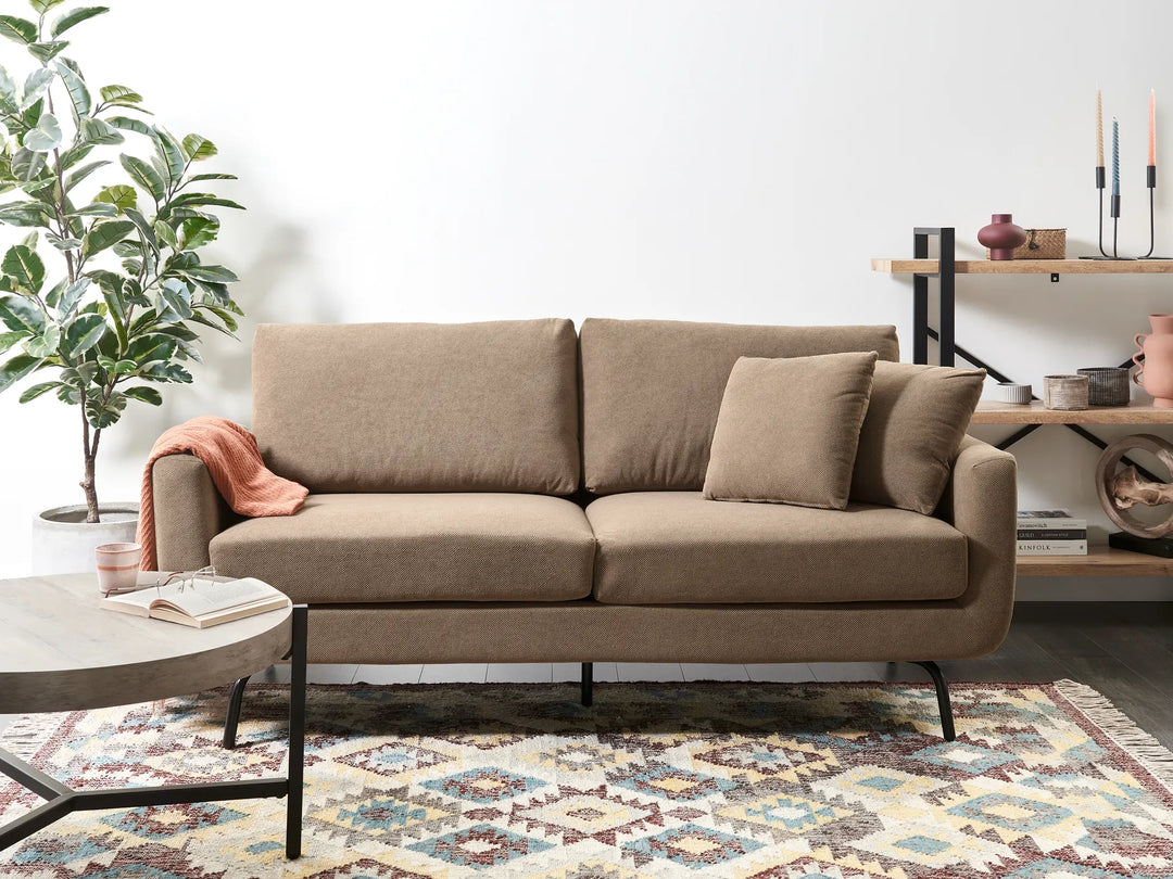 Brown sofa in a living room setting with a plant and coffee table.