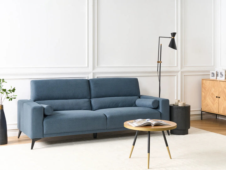 Blue sofa in a living room with a coffee table and lamp.