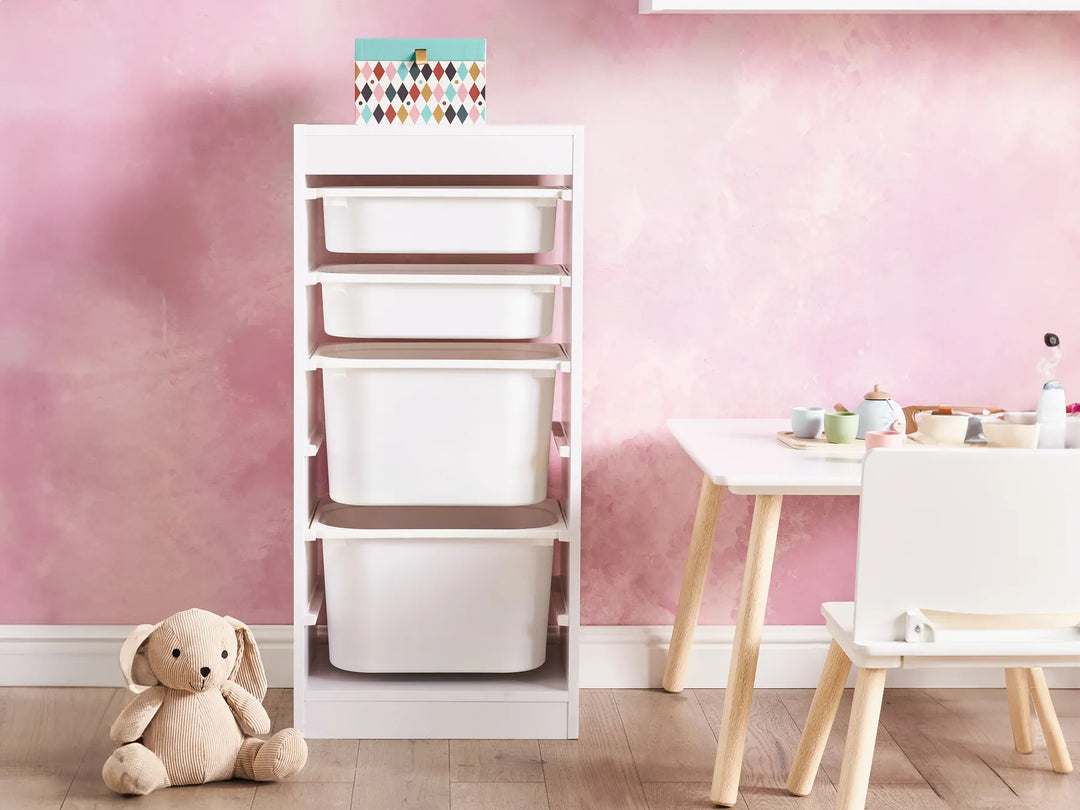 Children's room with storage unit, table, and teddy bear against a pink wall.