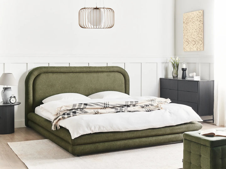 Green upholstered bed in a modern bedroom setting with white walls and minimal decor.
