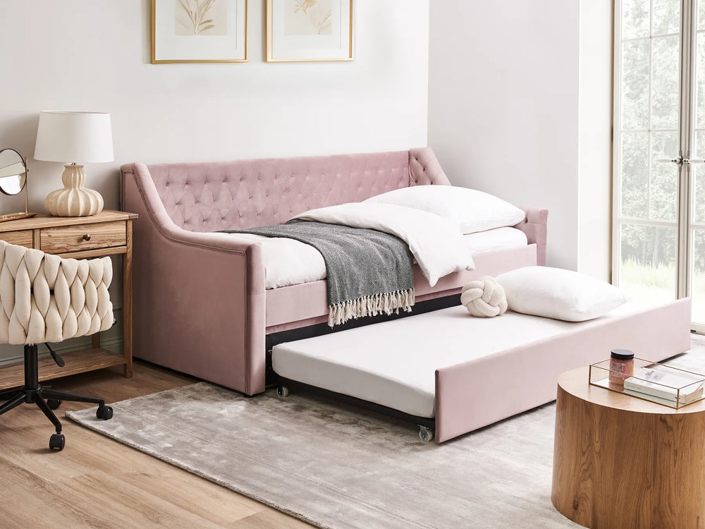 Pink sofa bed in a room with wooden furniture and decor.