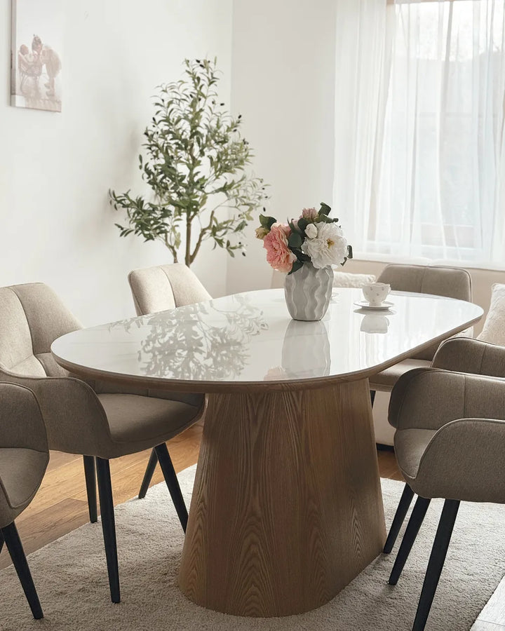 Dining room with a round marble table and chairs, featuring a vase of flowers.