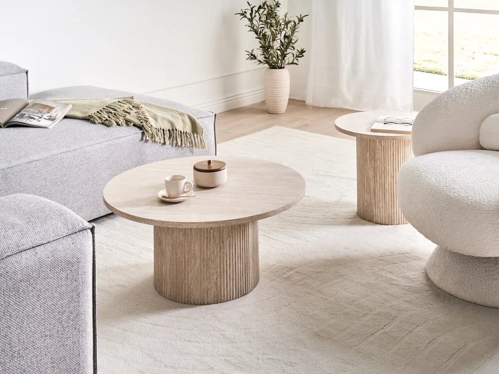 Modern living room with a round wooden coffee table, gray sofa, and white armchair.