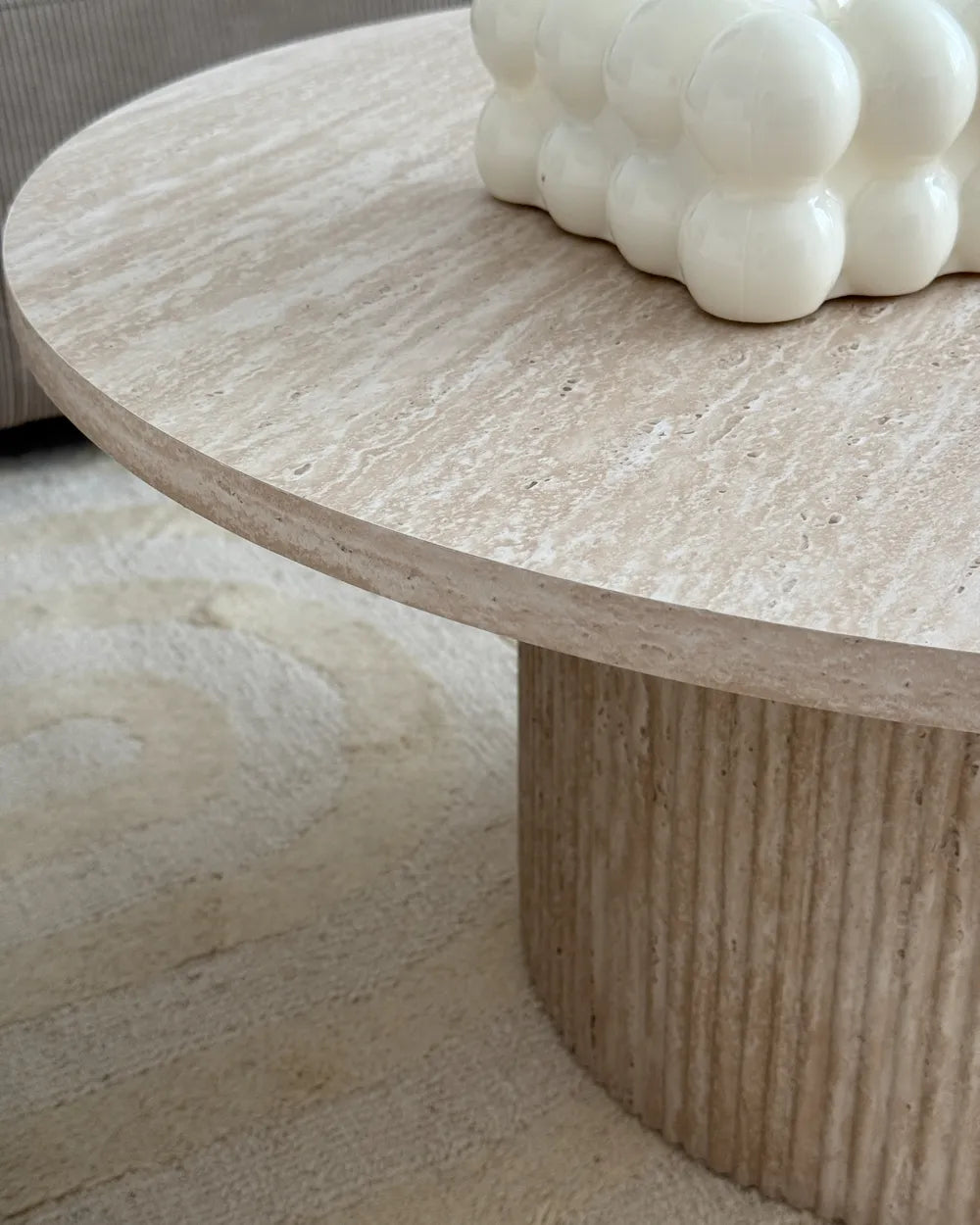 Round stone coffee table with a textured surface and decorative object on top.