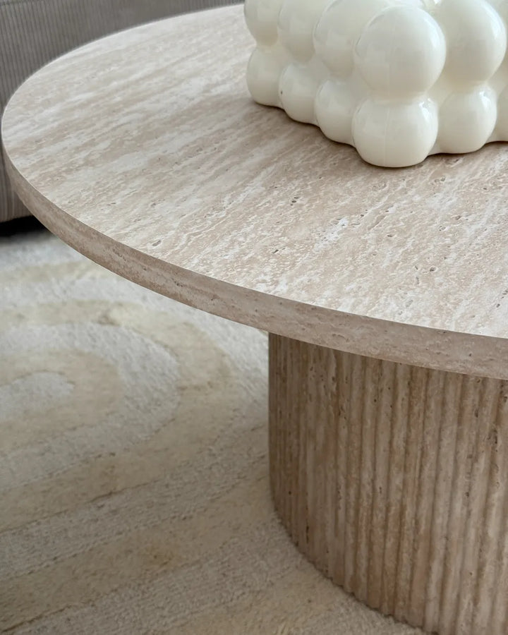 Round stone coffee table with a textured surface and decorative object on top.