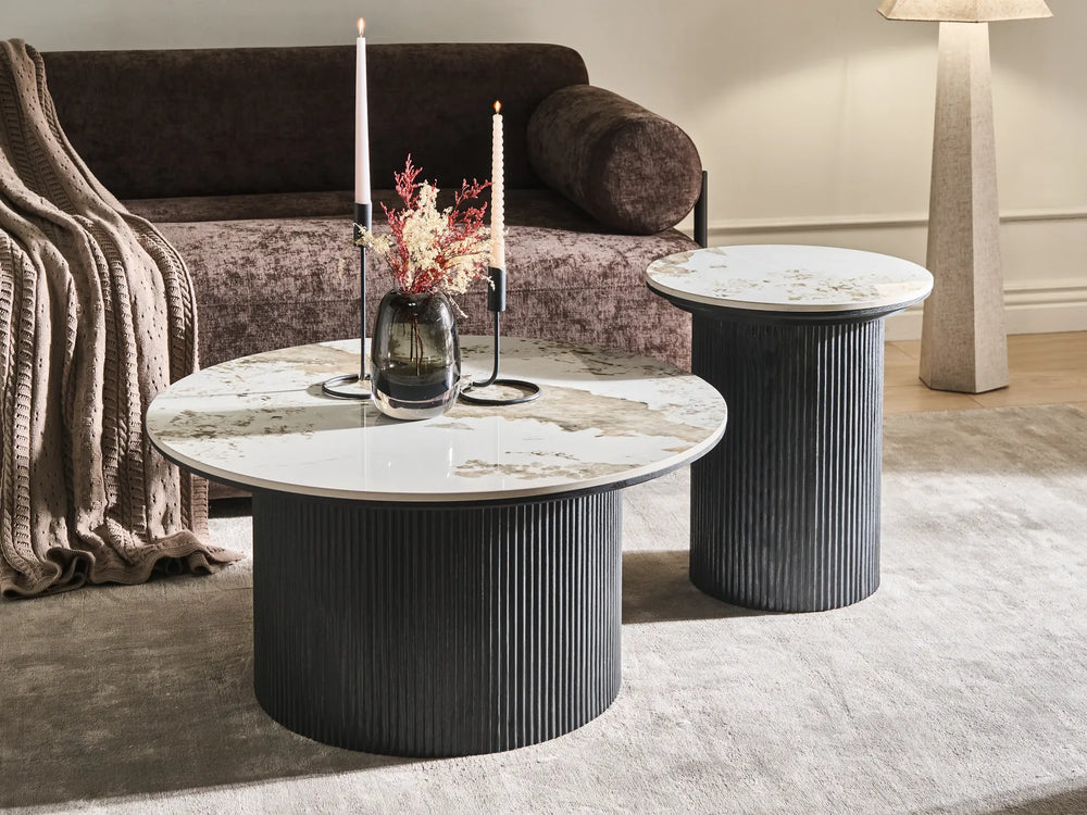 Round marble coffee table with decorative elements in a living room setting.