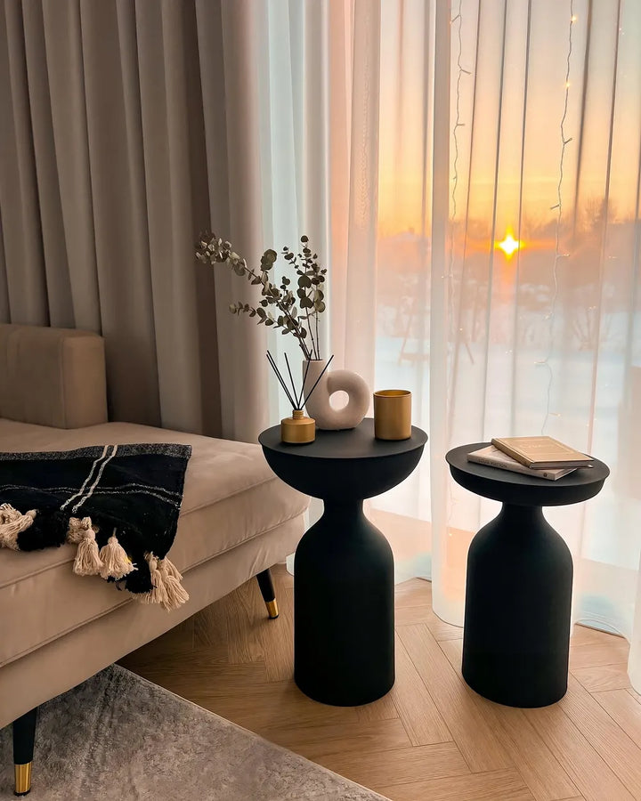 Modern living room with black side tables, beige sofa, and decorative elements.