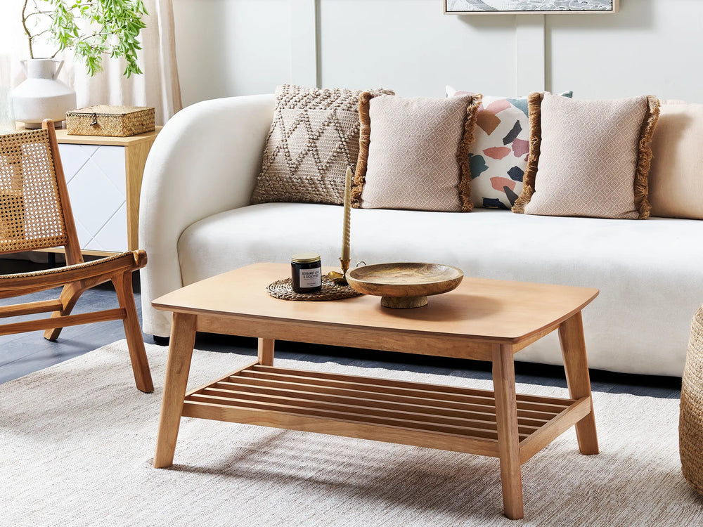 Wooden coffee table in front of a white sofa with decorative pillows in a living room setting.