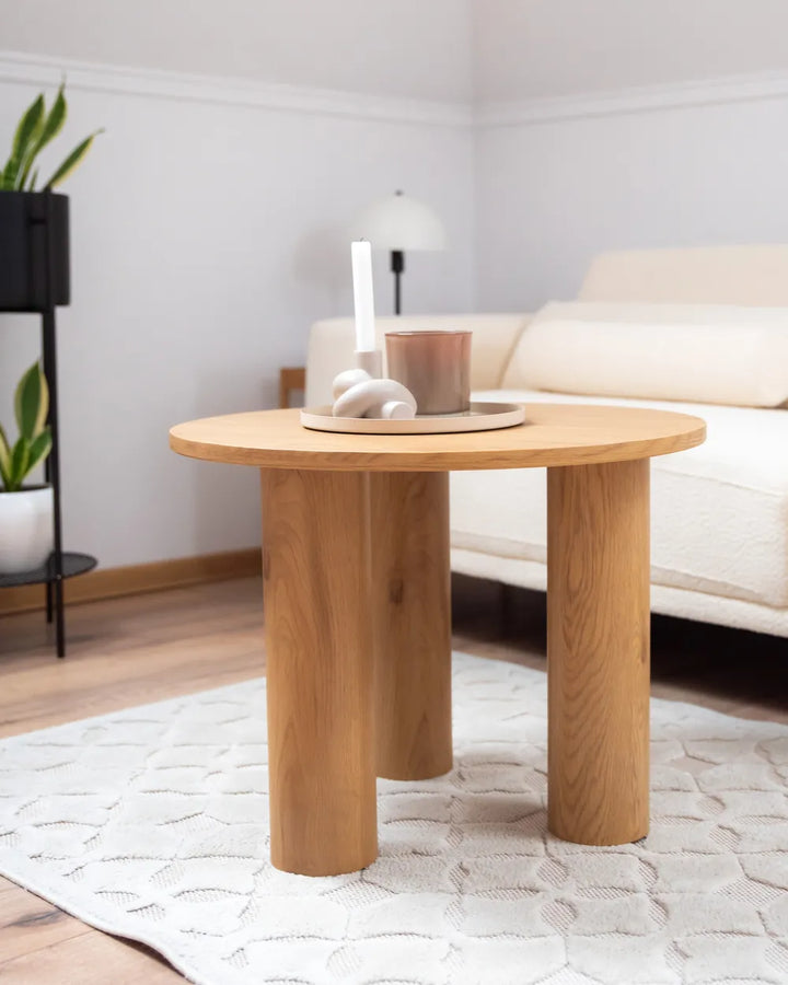 Wooden side table in a living room setting with a white sofa and decorative items.
