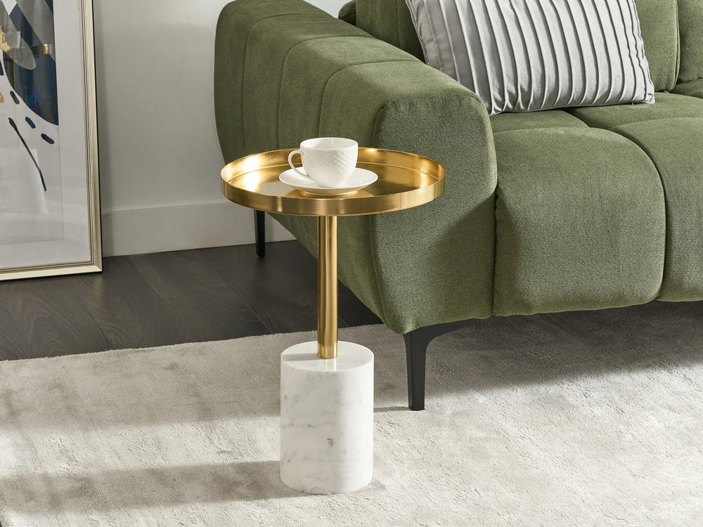 Gold side table with a white cup and saucer next to a green sofa.