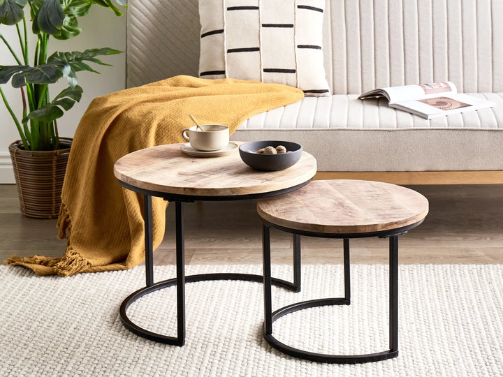 Two wooden coffee tables with black metal legs in a living room setting.