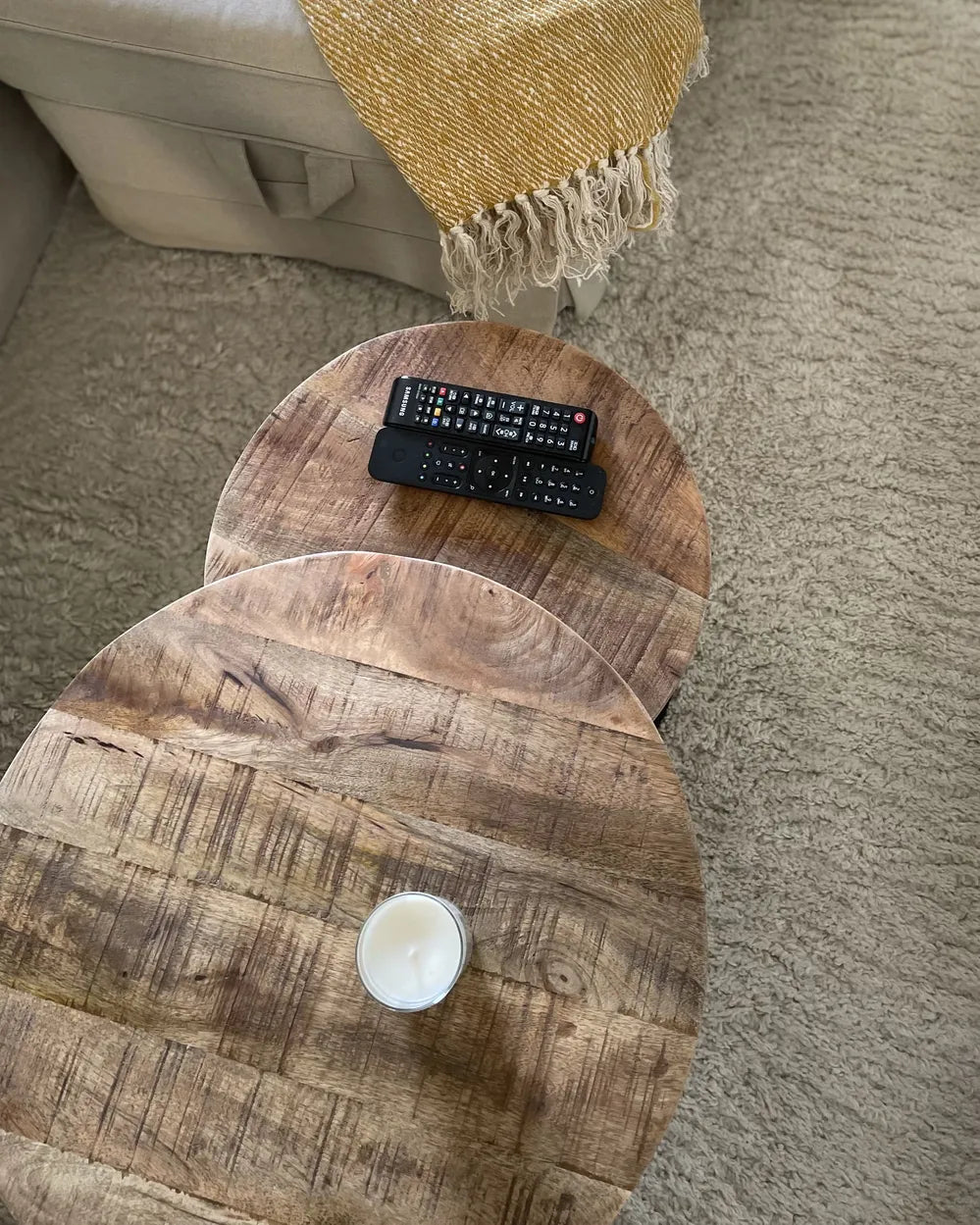 Wooden ottoman with a candle and remote control on a carpeted floor