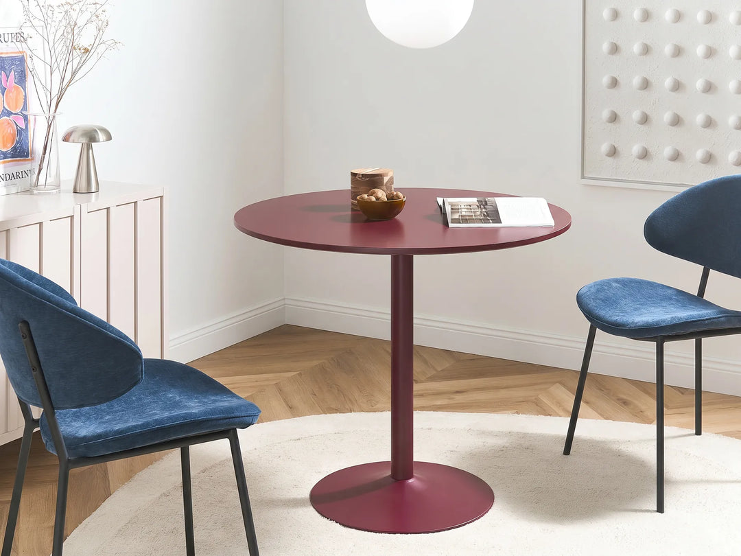 Round red table with two blue chairs in a modern room.