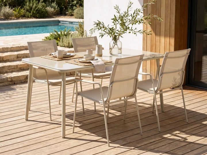 Outdoor dining set with table and chairs on a wooden deck near a pool.