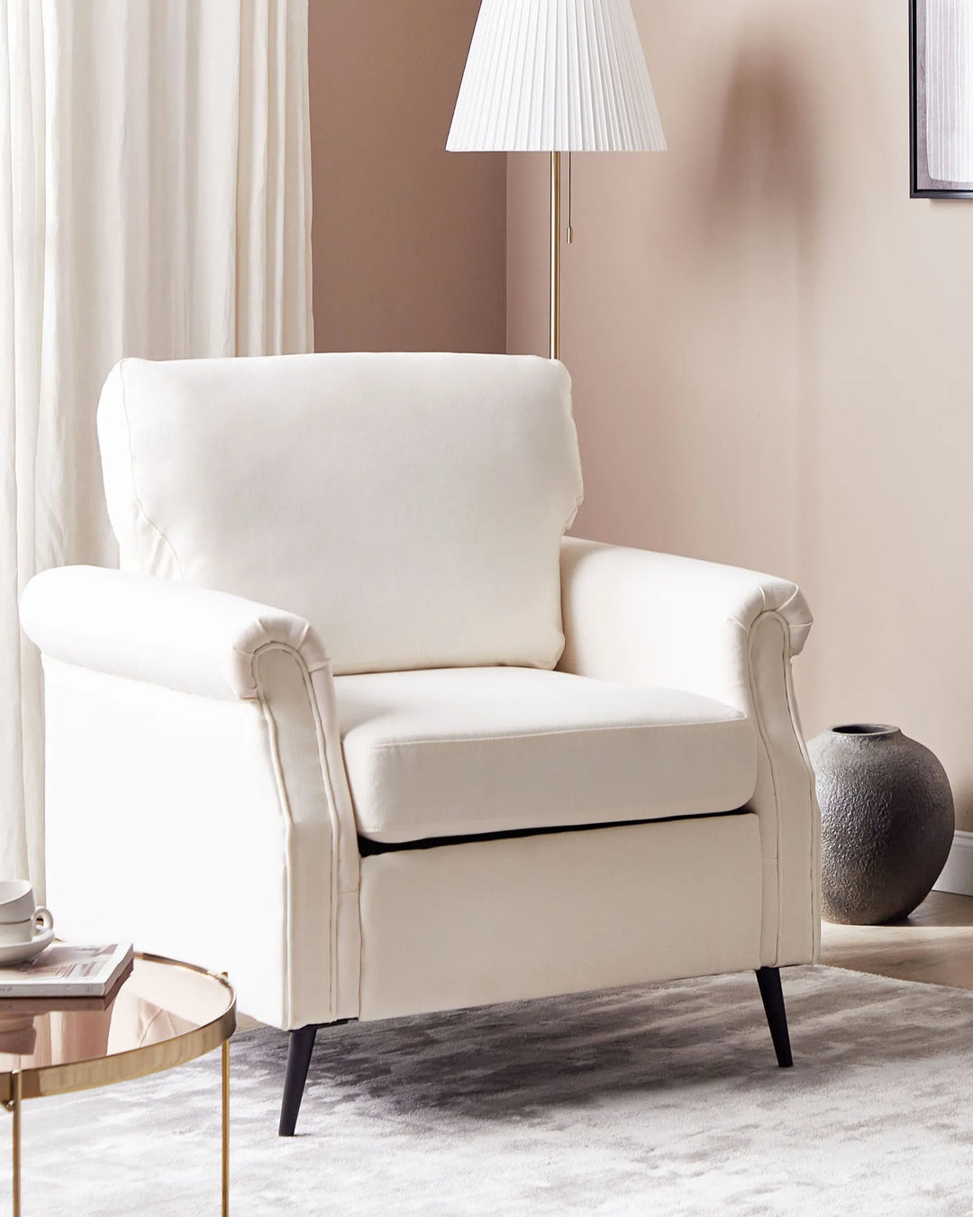 White armchair in a living room setting with a lamp and vase.