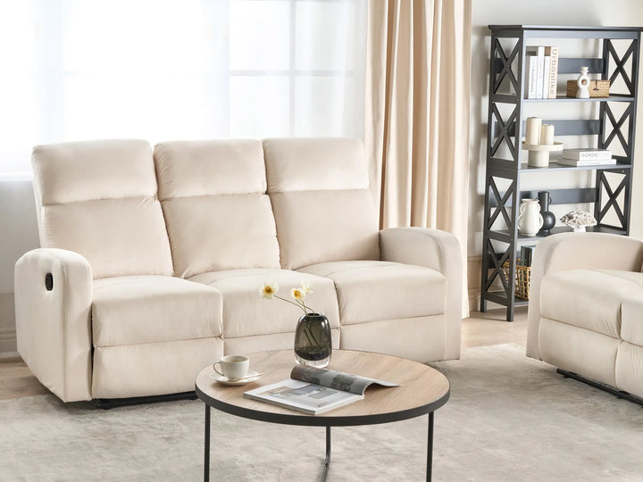 Beige recliner sofa in a living room setting with a coffee table and decorative items.