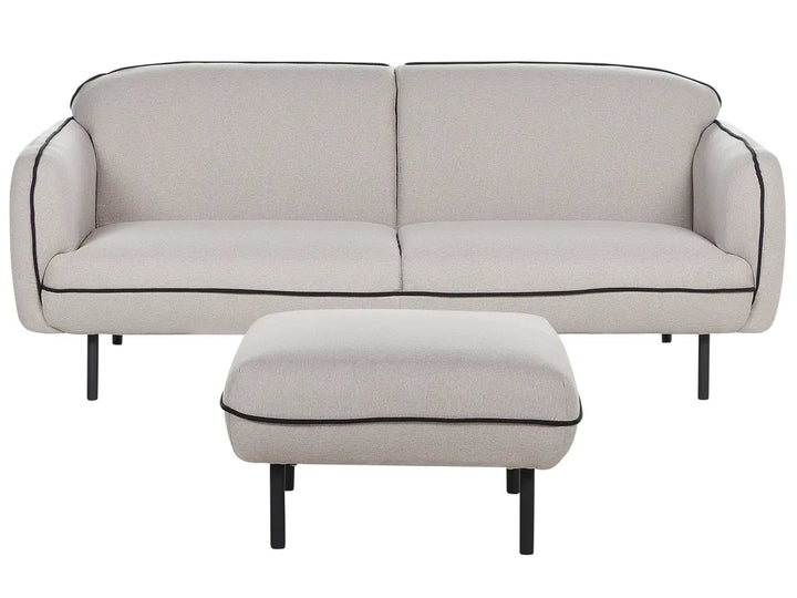 Beige sofa with black piping and matching ottoman on a white background