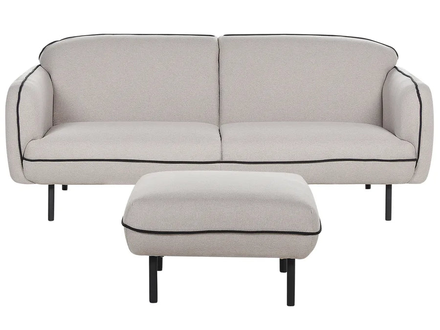 Beige sofa with black piping and matching ottoman on a white background
