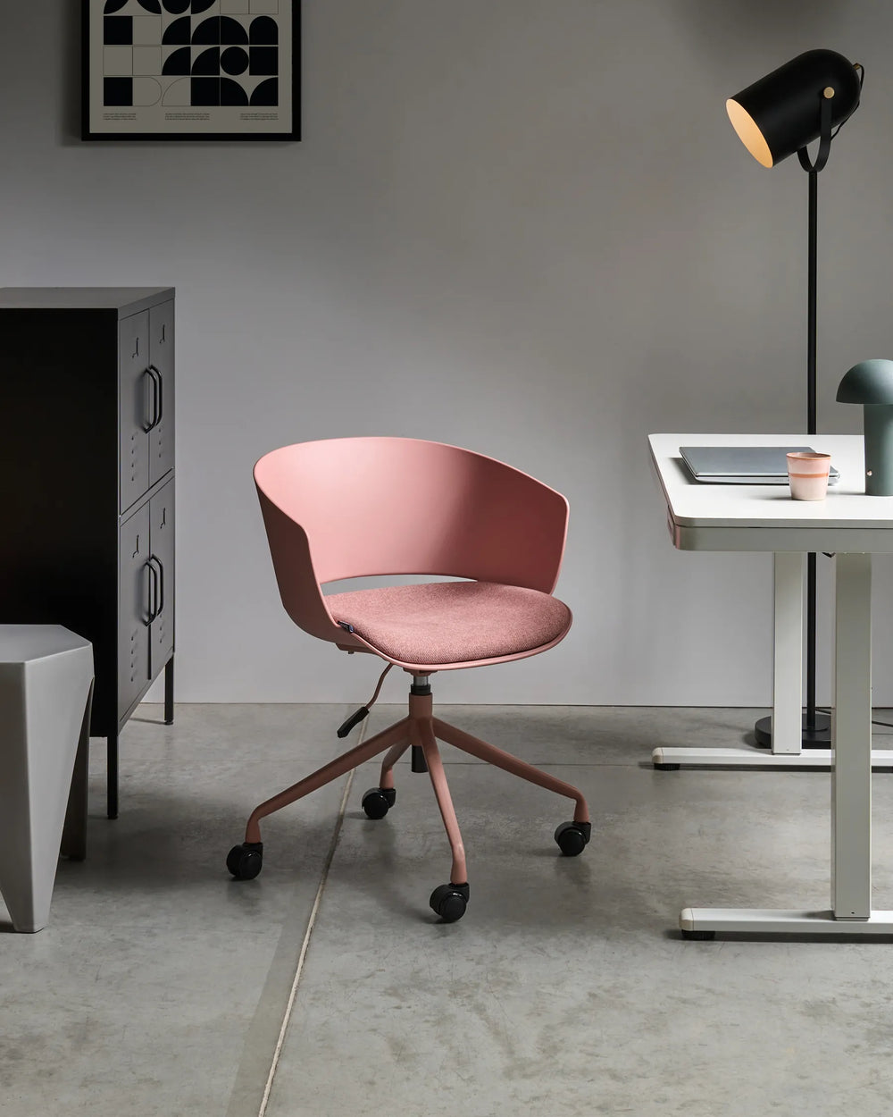 Pink office chair in a modern office setting with a desk and lamp.