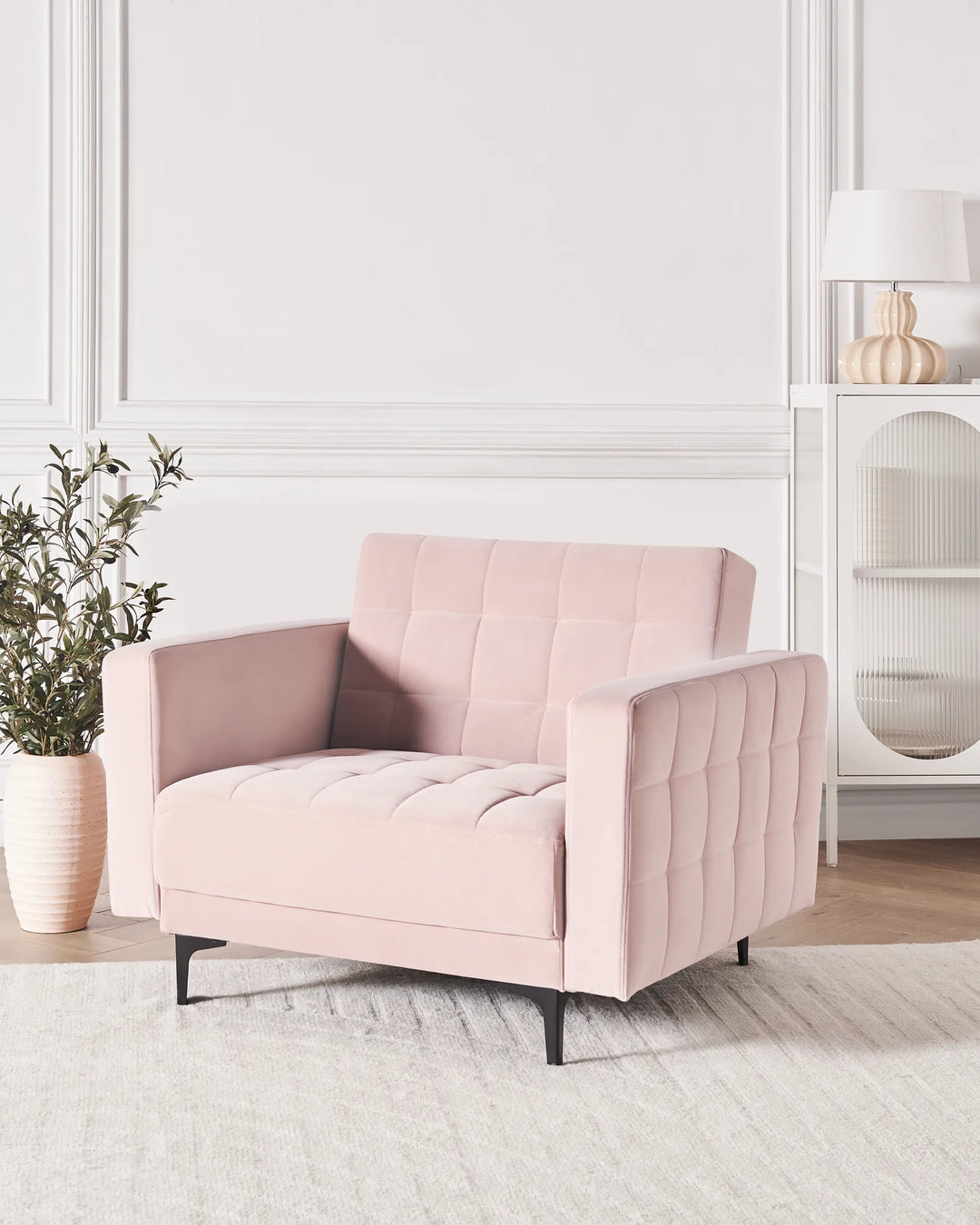 Pink armchair in a modern living room with a white wall and decorative elements.