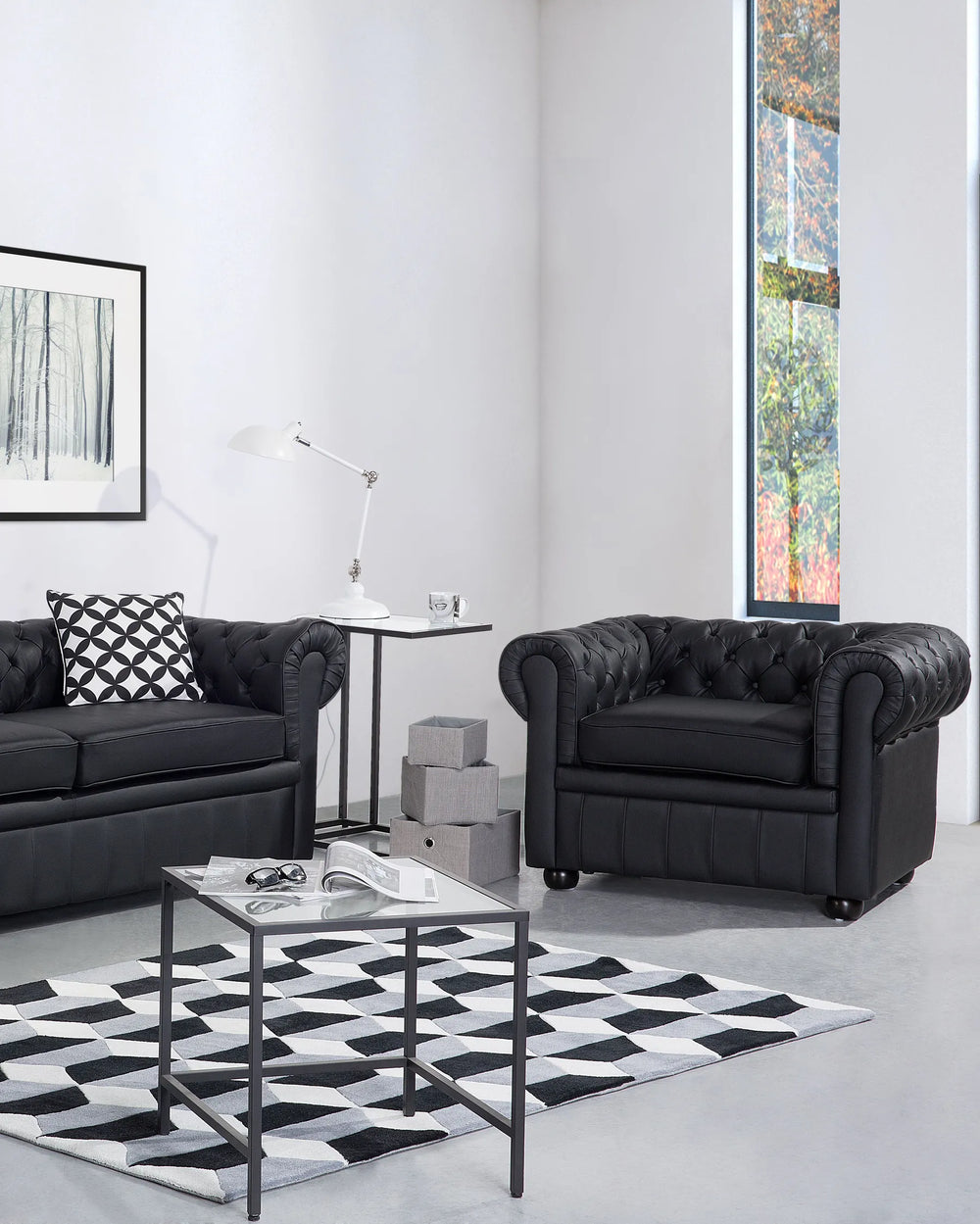 Modern living room with black Chesterfield sofas, a glass coffee table, and decorative items.