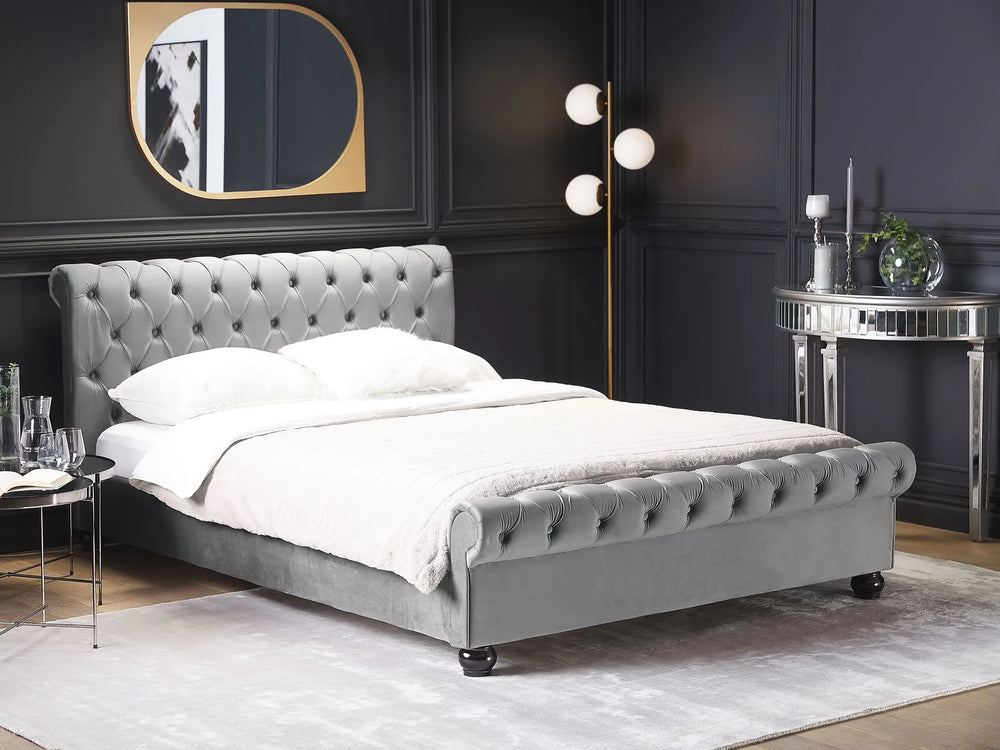 Gray upholstered bed in a stylish bedroom with dark walls and modern decor.