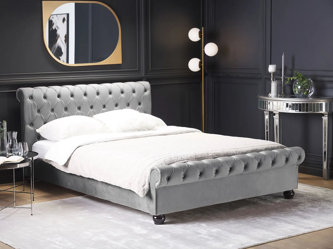 Gray upholstered bed in a stylish bedroom with dark walls and modern decor.
