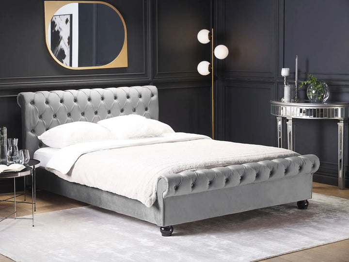 Gray upholstered bed in a stylish bedroom with dark walls and modern decor.