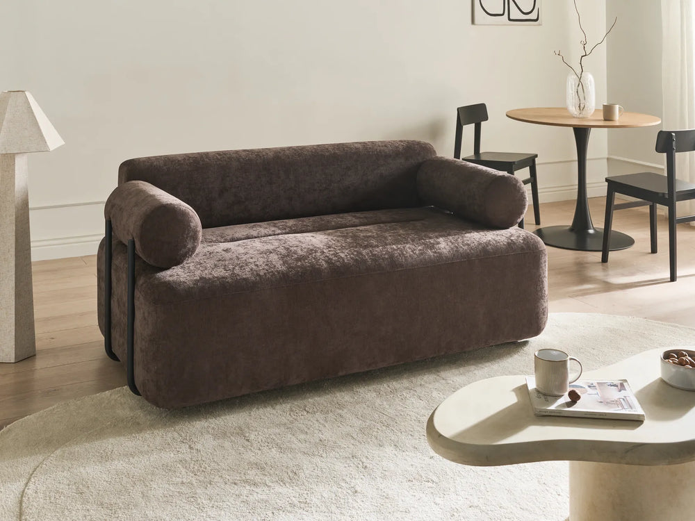 Brown sofa in a living room setting with a coffee table and chairs.