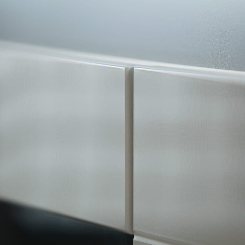 Close-up of a white ceramic tile with a subtle pattern on a light gray background