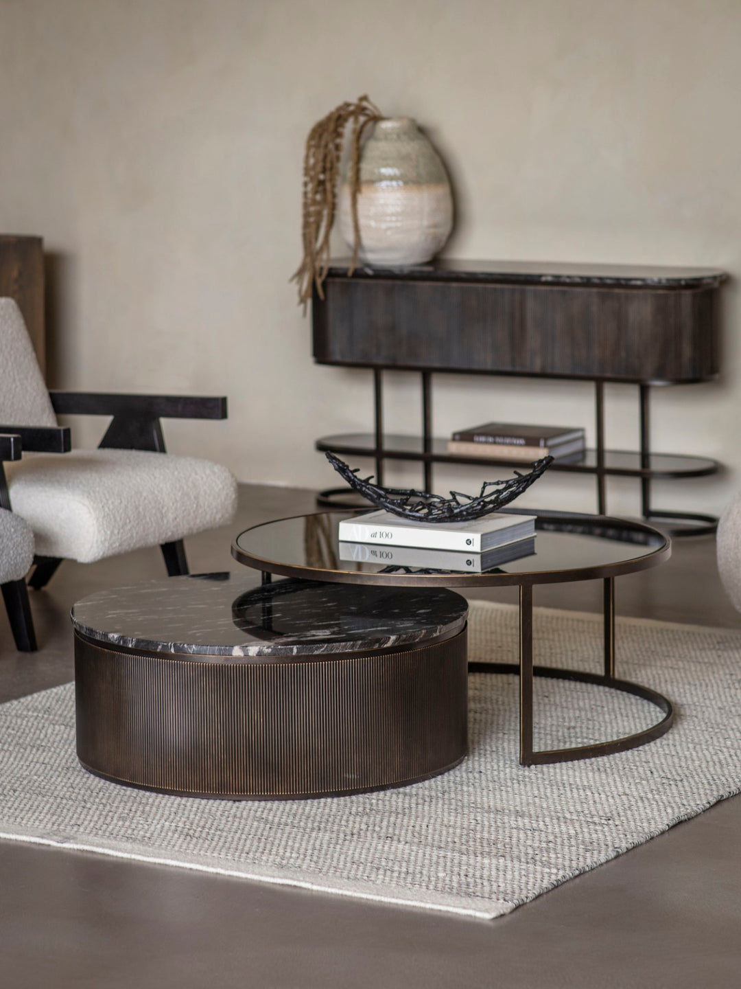 Modern living room with round coffee table, shelves, and decorative items.