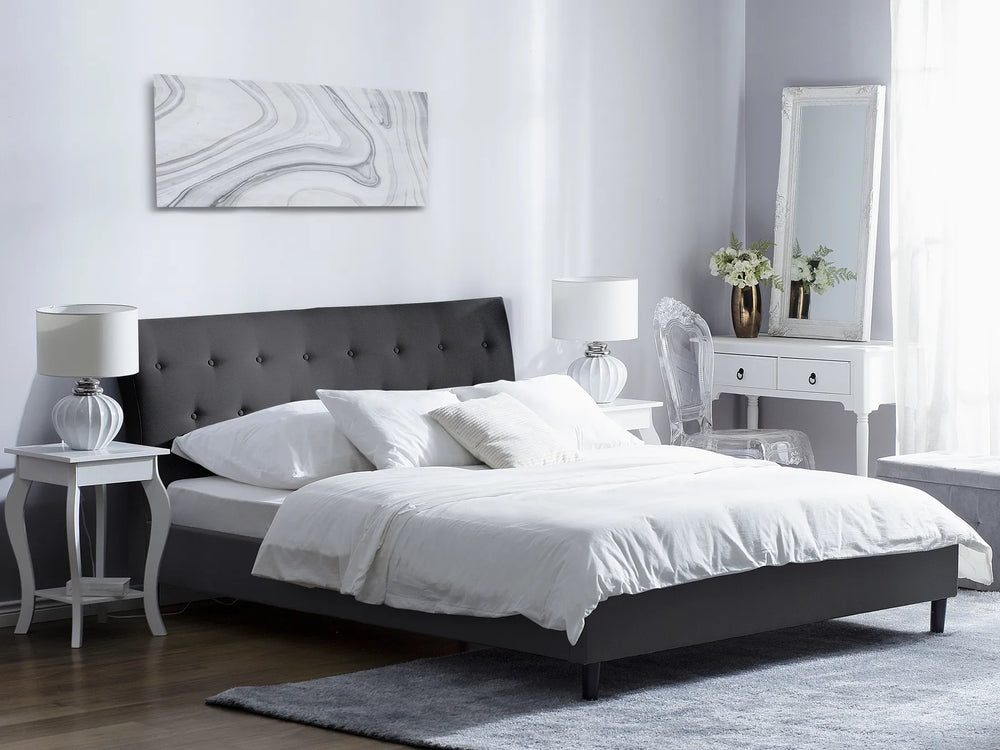 Modern bedroom with a black upholstered bed, white bedding, and decorative items.