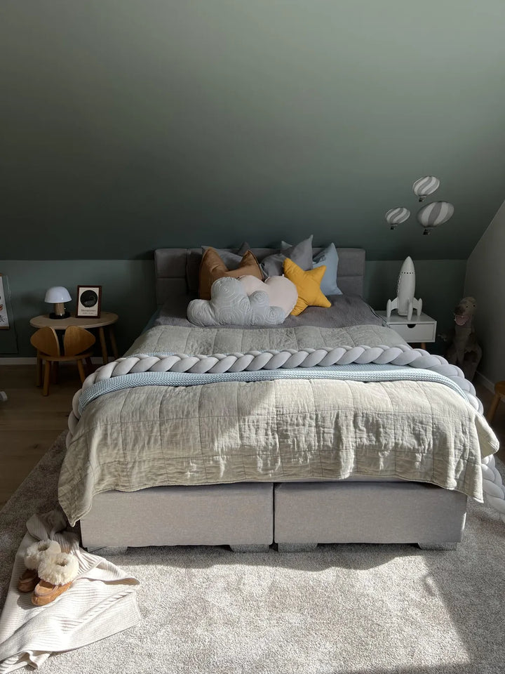 Bedroom with a bed featuring colorful pillows and a nightstand with decor items.