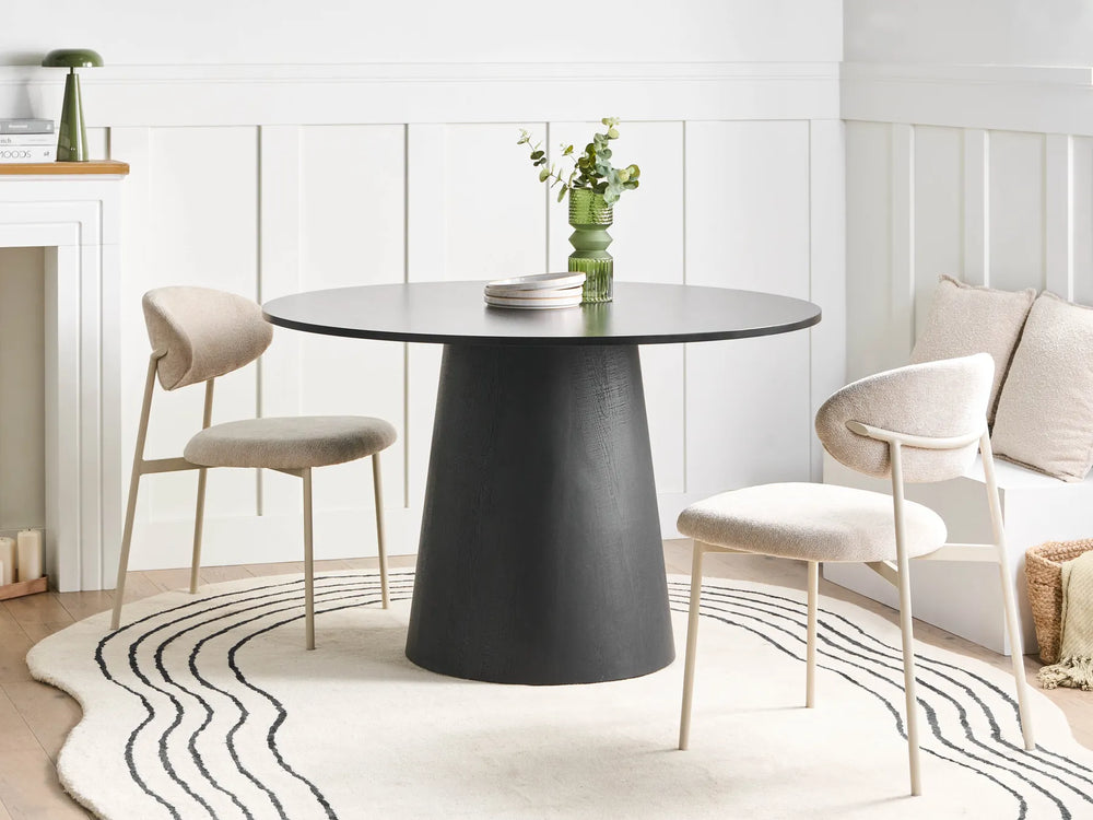Dining area with a black round table and chairs in a bright room.
