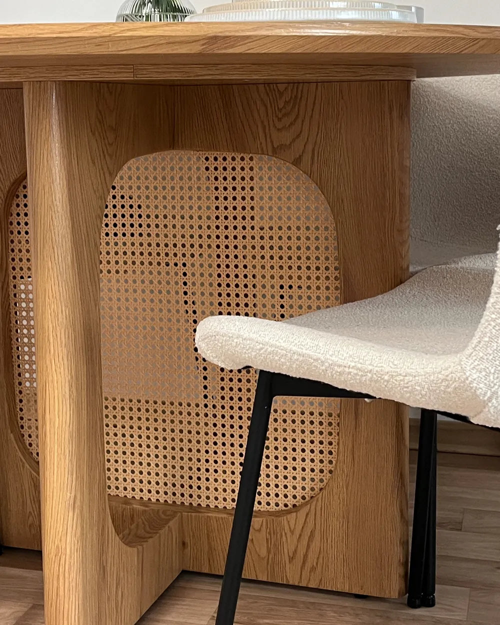Wooden table with a chair featuring a woven backrest and black legs.
