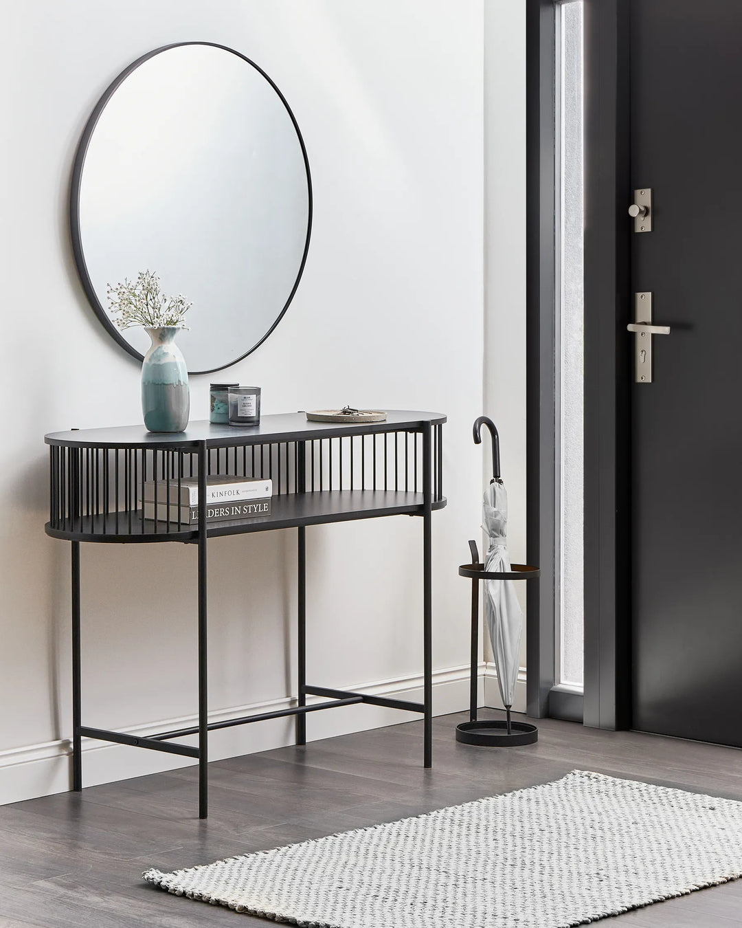 Modern interior with a black console table, round mirror, and decorative items.