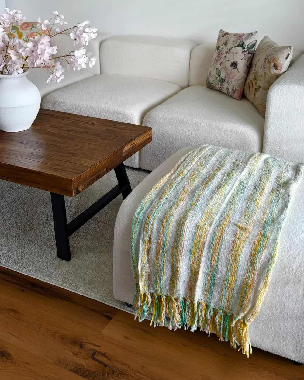 Living room with a beige sofa, wooden coffee table, and colorful blanket.