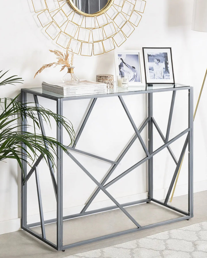 Console table with geometric design, decorative items, and a mirror in a room setting.