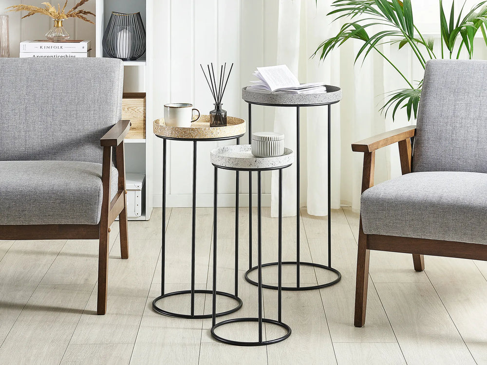 Set of three round side tables with black metal legs in a living room setting.