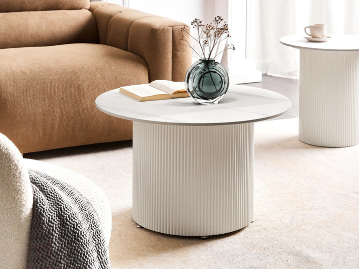 Round coffee table with a vase and book in a living room setting