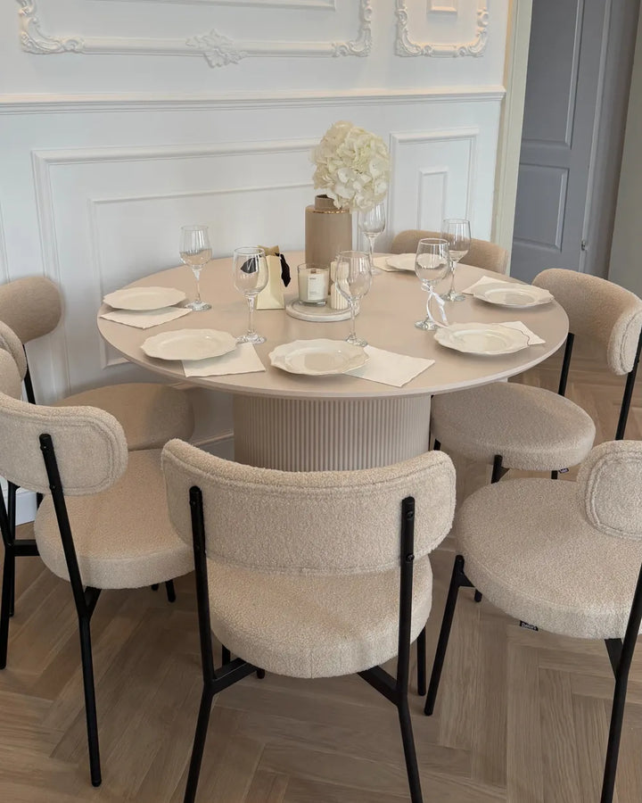 Round dining table set with chairs in a stylish room.