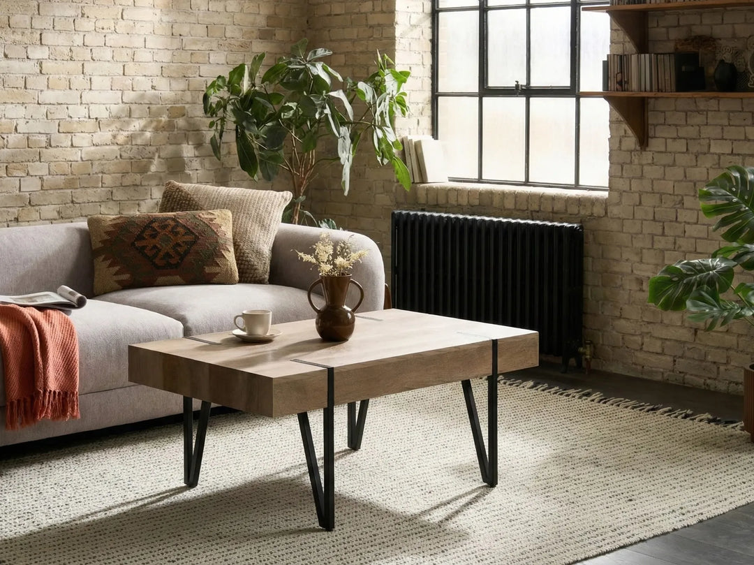 Modern living room with a gray sofa, wooden coffee table, and brick wall.