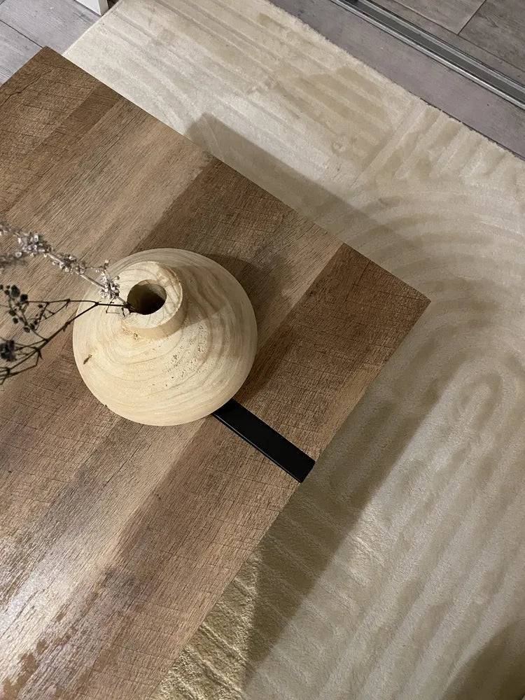 Worn wooden vase on a textured surface with a neutral color palette
