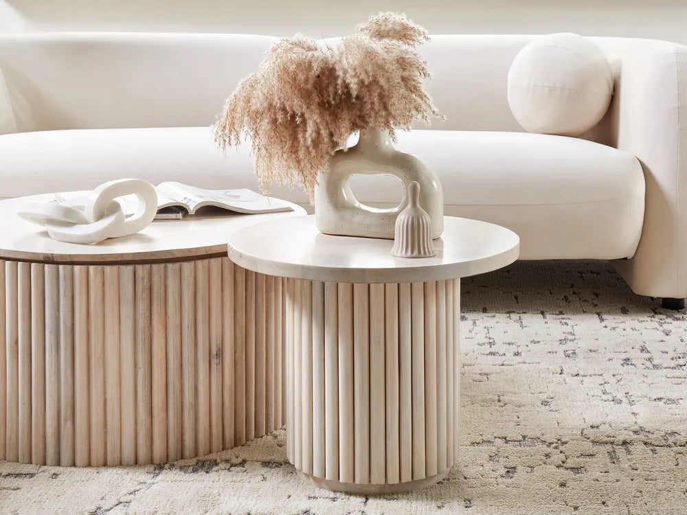 Round wooden side table with decorative items in a living room setting