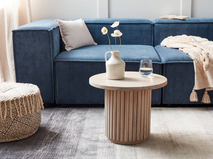 Blue sectional sofa with a wooden side table and decorative items in a living room.